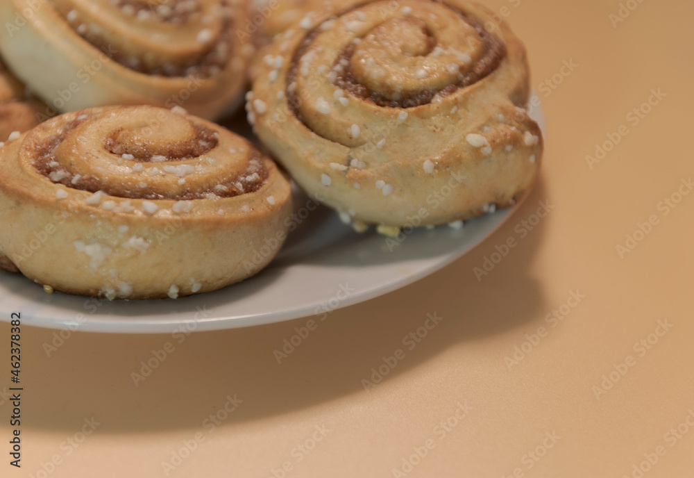 Cinnamon rolls on a white plate with an orange - peach background
