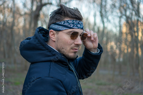 Portrait of a young and stylish man in sunglasses and a bandana. Male model showing fashion. Style concept. © Danny_Houston87