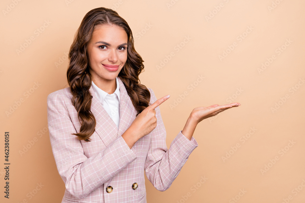 Photo of positive adorable person finger direct hand palm hold empty space isolated on beige color background Photo of positive adorable person finger direct hand palm hold empty space isolated on beige color background