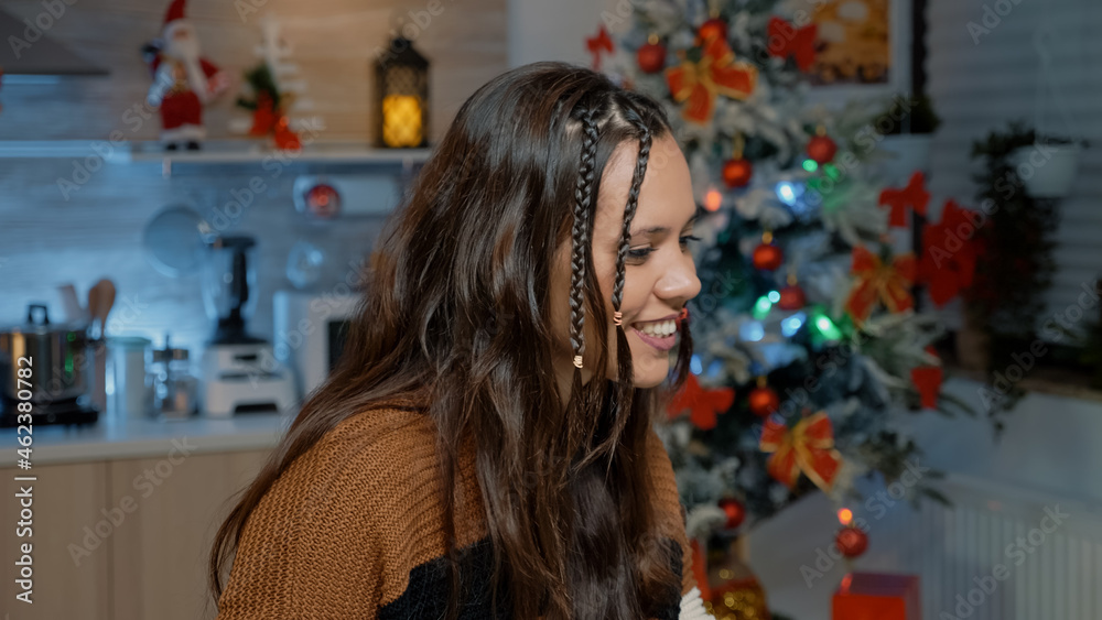 Young woman using modern technology for video call communication with friends in festive kitchen. Caucasian person making preparations on laptop for christmas day dinner celebration Young woman using modern technology for video call communication with friends in festive kitchen. Caucasian person making preparations on laptop for christmas day dinner celebration