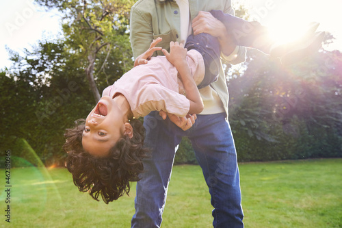 Boy being held upsidedown in garden with mouth open photo