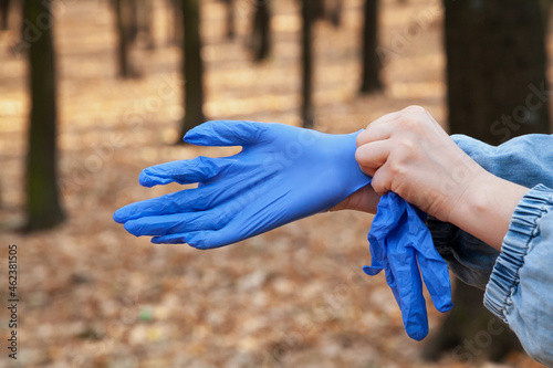 Hands put on rubber gloves in forest