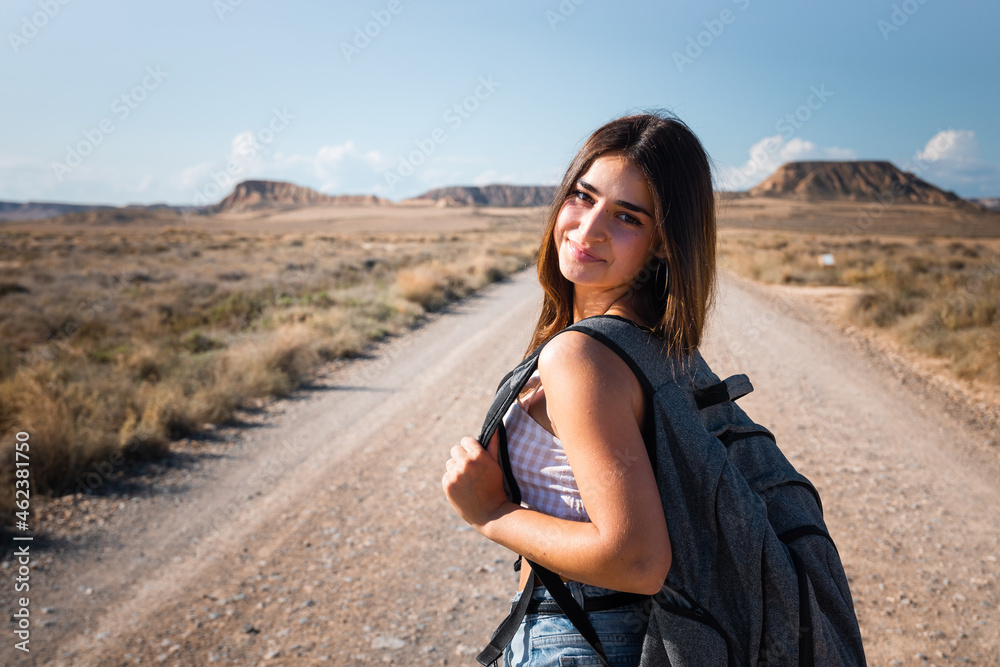 Young caucasian woman with a grey backpack walking in the middle of a dessert at Bardenas, Navarre, Basque Country. Young caucasian woman with a grey backpack walking in the middle of a dessert at Bardenas, Navarre, Basque Country.