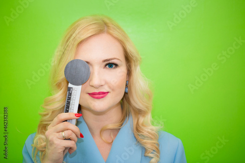 A beautiful girl is undergoing an ophthalmologic examination, checking her eye health and visual acuity. Ophthalmologist conducts vision diagnostics. On a green background with copy space.