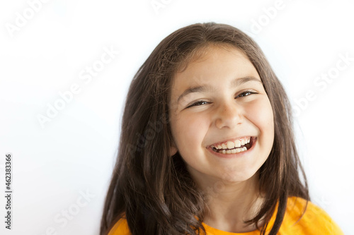 Portrait of happy positive smiling child girl with a long hair in yellow T-shirt isolated on white background © kaganskaya115