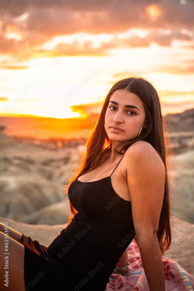 Young caucasian woman with a sexy black dress at sunset time at Bardenas Reales, Navarre, Basque Country.