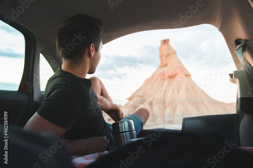 Young caucasian man eating and with his laptop while camping next to Castildetierra natural monument at Bardenas Reales desert, Navarra, Basque Country.