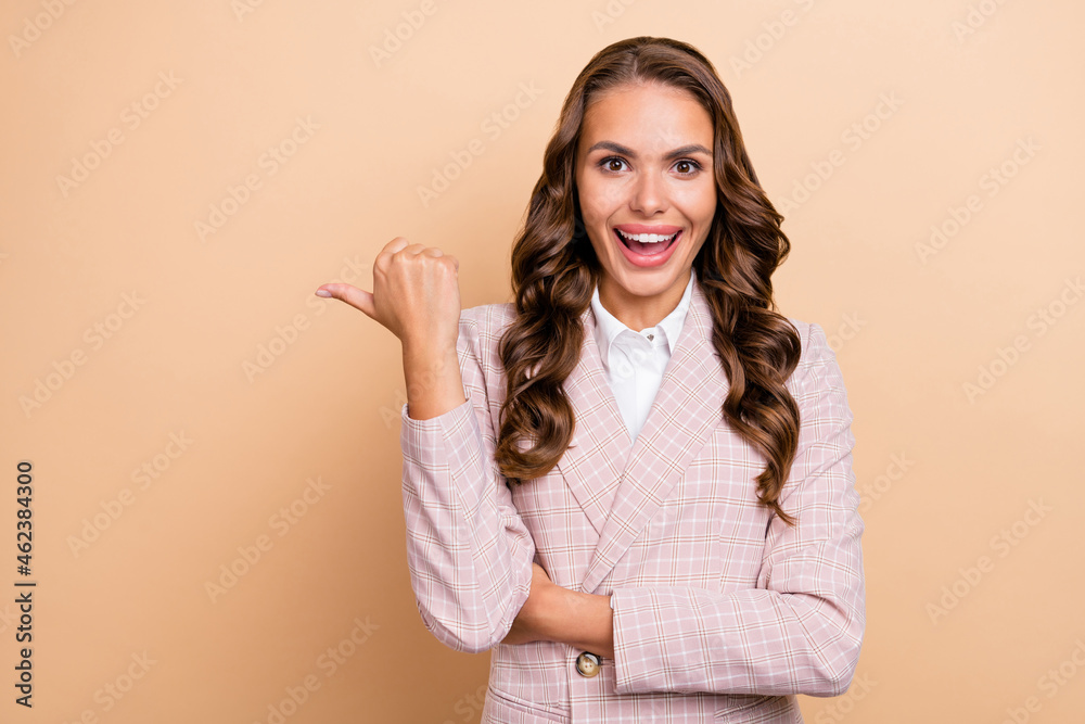 Portrait of impressed astonished lady indicate thumb empty space isolated on beige color background Portrait of impressed astonished lady indicate thumb empty space isolated on beige color background