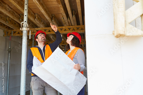 Architektin und Handwerker kontrollieren Holzdecke