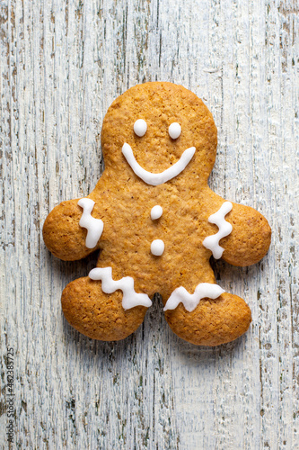 One Christmas gingerbreads man with patterns of glaze on a white wooden background.