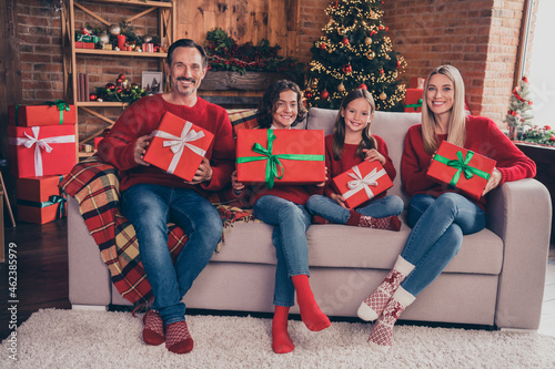 Portrait of beautiful handsome cheery family holding giftboxes sitting on sofa advent spirit at decorated loft home indoors