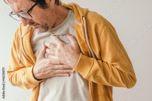 Foto Aching chest, adult male with painful grimace pressing the upper abdomen with hi