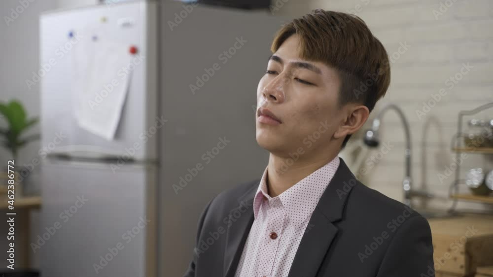 headshot of an exhausted Asian business man with eyes close is falling asleep at dining table in the early morning before work at home. headshot of an exhausted Asian business man with eyes close is falling asleep at dining table in the early morning before work at home.