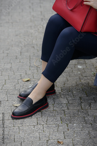 Female fashion concept. Womans legs in a black shoes with red line