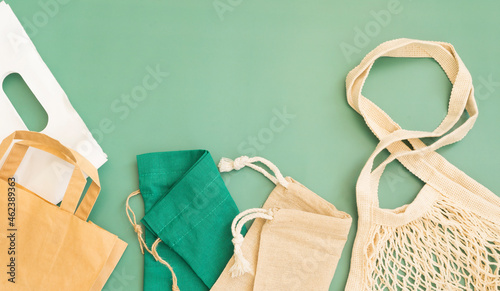 Variety of eco bags and shopping bags on green background