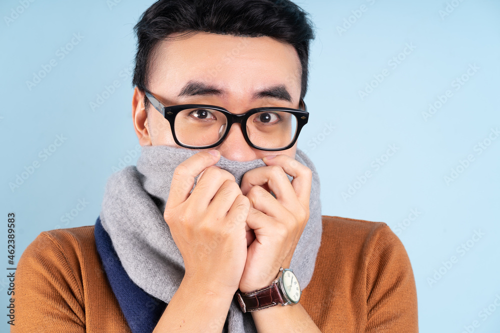 Asian man wearing winter clothes on blue background Asian man wearing winter clothes on blue background