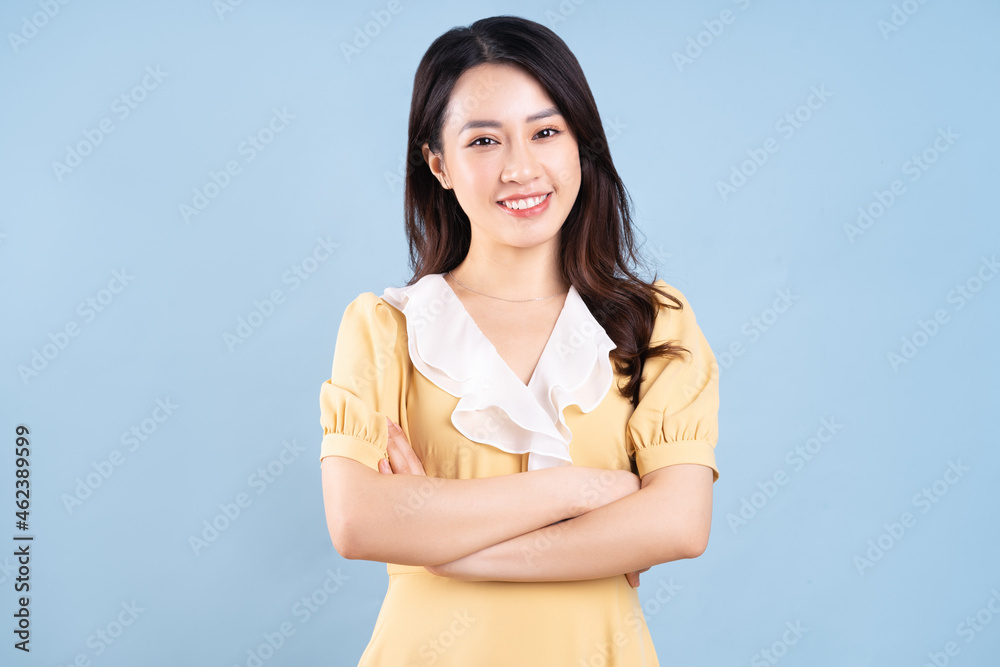 Beautiful Asian young woman wearing yellow dress on blue blackground Beautiful Asian young woman wearing yellow dress on blue blackground