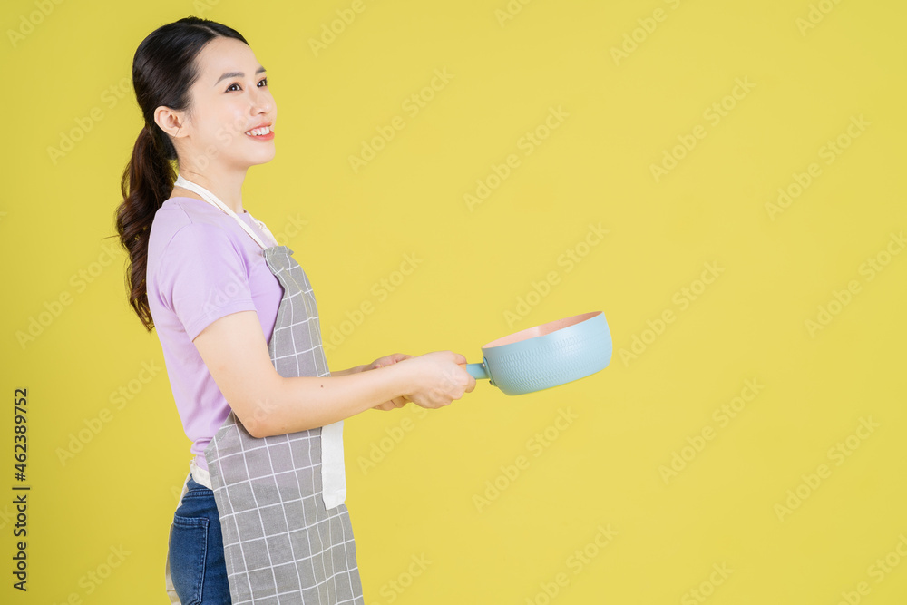Young Asian housewife posing on yellow background Young Asian housewife posing on yellow background