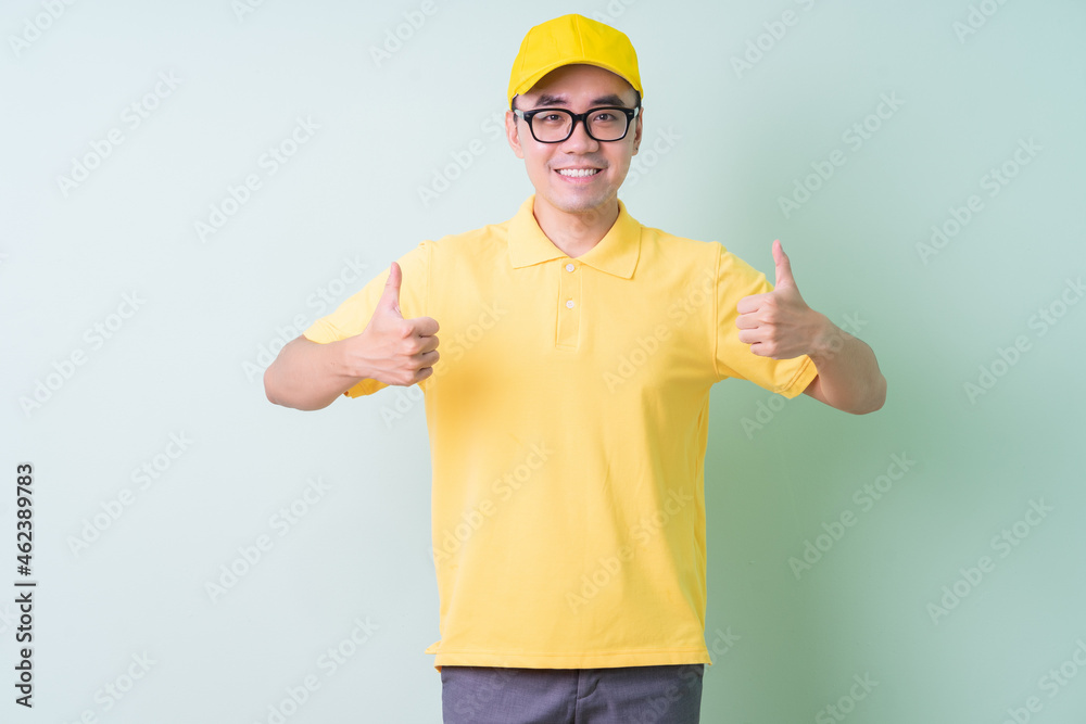 Young Asian delivery man posing on green background Young Asian delivery man posing on green background