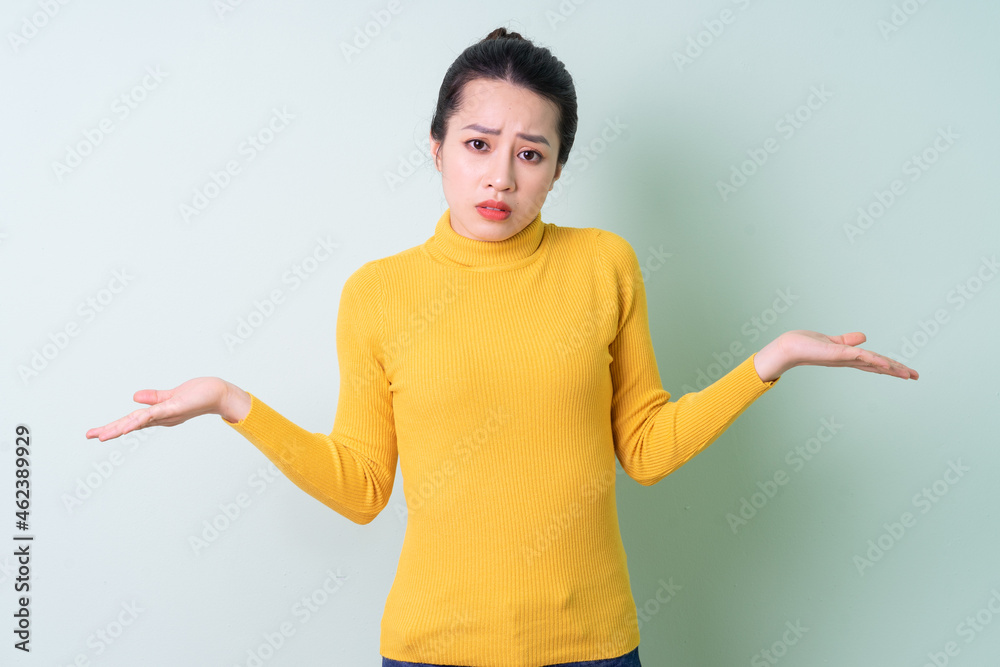 Beautiful young Asian woman wearing sweater on green background Beautiful young Asian woman wearing sweater on green background