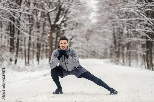 Fit sportsman doing stretching and warmup exercises in forest at snowy winter day. Healthy life, warmup, cold weather © dusanpetkovic1