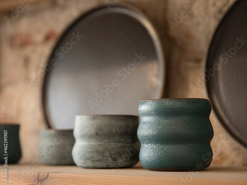 Handmade empty clay dishes composition on a wooden shelf in a shop