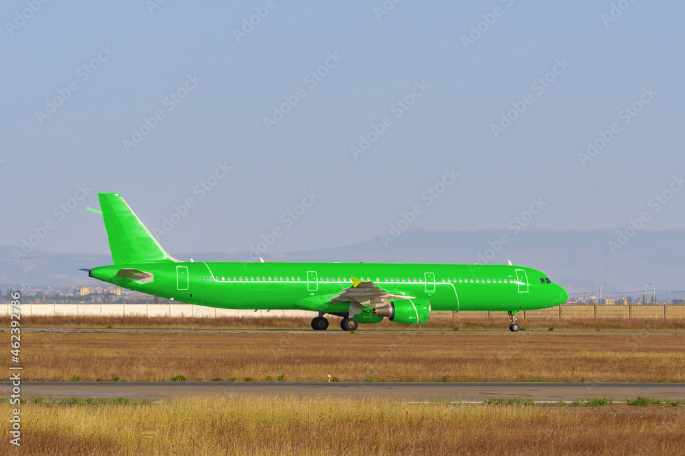 Green passenger airplane at the airport on sunny day