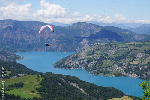 paraglider over the mountains and lake of serre ponçon alps france