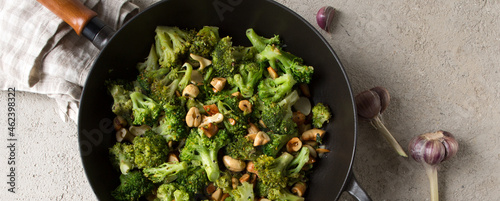 frying pan with stir fry with broccoli and cashews on the table photo