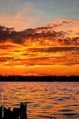 Beautiful bright orange sunset over the river surface. Vertical image