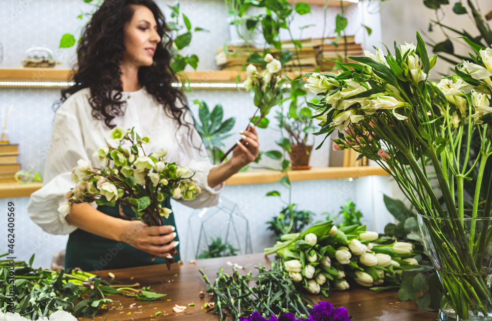 Attractive young woman florist is working in a flower shop. Attractive young woman florist is working in a flower shop.