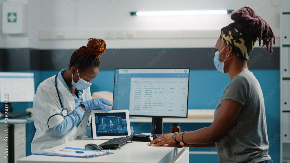 Medic and patient looking at human body analysis for osteopathy diagnosis in cabinet. Doctor with skeleton scan on digital tablet talking to young woman about osteoporosis treatment.