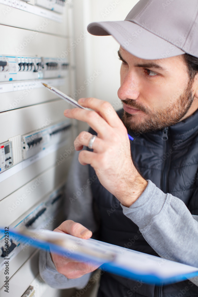 young adult electrician screwing equipment in fuse box