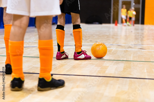 Children on Indoor Soccer Training. Kids Playing Futsal on Wooden Floor. Legs of Kids Soccer Players with Orange Futsal Ball. Players Standing in Two Opposite Rows on Practice Class