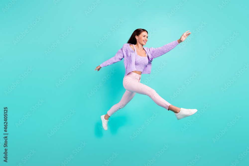 Photo of pretty charming young woman dressed purple clothes running fast jumping high smiling isolated teal color background