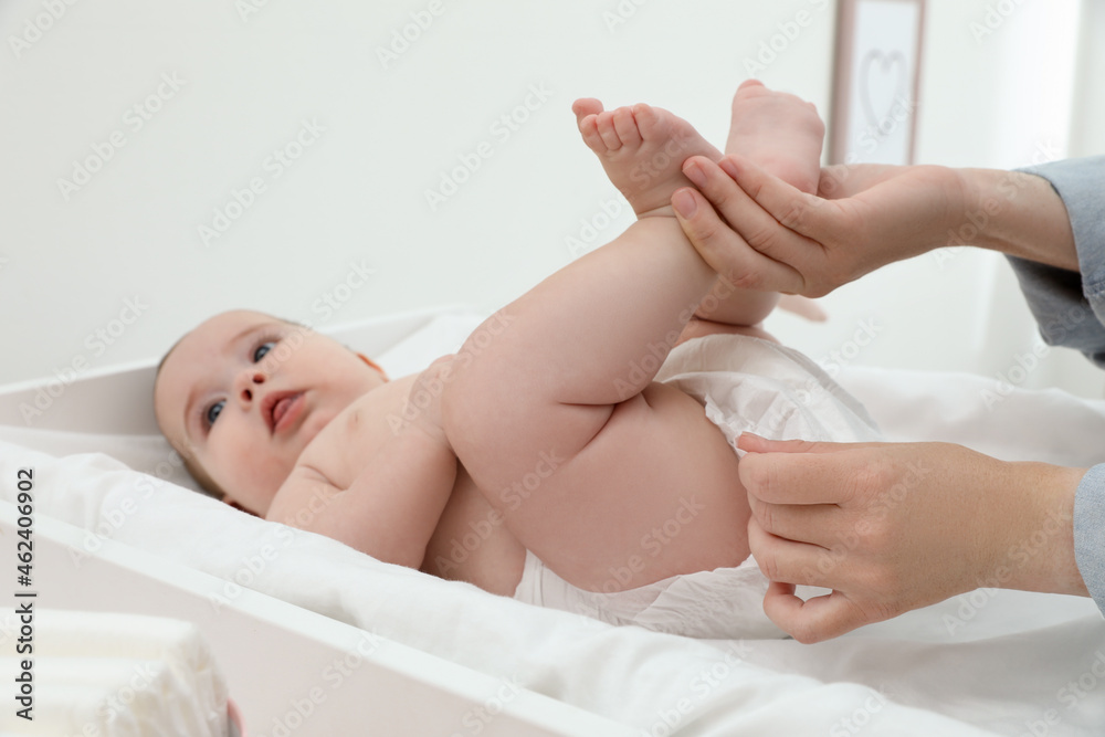 Obraz premium Mother changing baby's diaper at home, focus on hands