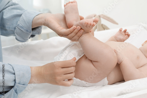 Mother changing baby's diaper on table at home, closeup