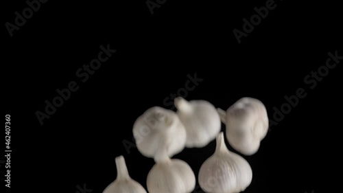 Slow motion shot of flying up and falling garlic bulbs in the air on a black background.