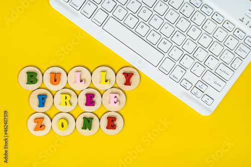 Layout of wooden alphabet on wooden tiles, keyboard with text BULLY FREE ZONE. Cyberbullying concept photo