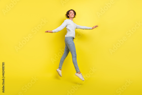 Photo of inspired lady jump move go wear blue pullover jeans footwear isolated yellow color background