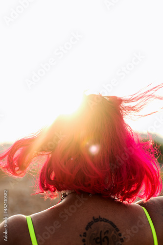 portrait of dark skinned Indian woman in Malaysia, smiling and dancing in a barren open field, during sunset, golden hour