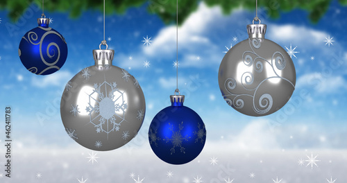 Image of christmas balls over snowflakes on blue background