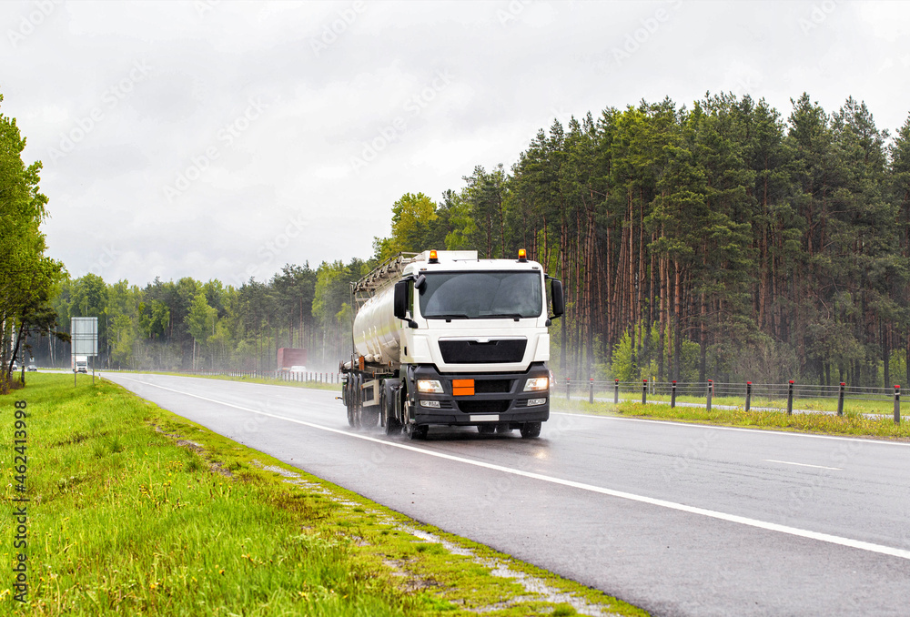 A special vehicle for the transport of explosive substances travels along the road and transports oil products in rainy weather. Concept of the industry and transportation of petroleum products 