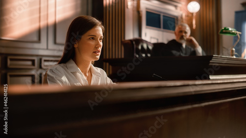 Court of Law and Justice Trial Stand: Portrait of Beautiful Female Victim Giving Heartfelt Testimony, Judge and Jury Listening. Dramatic Speech of Empowered Witness against Crime, Prejudice, Injustice photo
