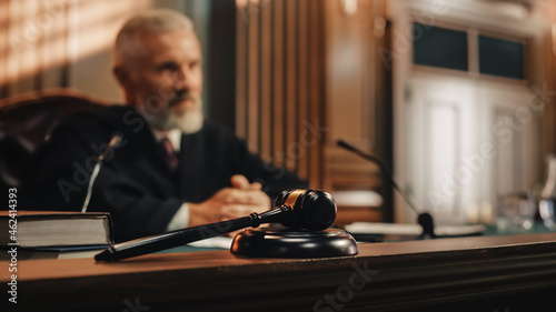 Cinematic Court of Law and Justice Trial: Honorable Male Judge Discussing Pleaded Case, Decision Guilty or Innocent Verdict after Hearing Arguments. Blurred Shot with Focus on Gavel photo