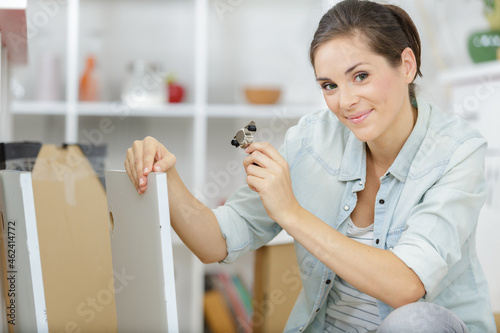 young woman assembling furniture in new apartment photo