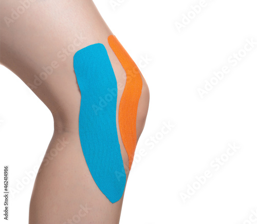 Female knee joint with orange and blue tape for microcirculation and joint fixation. White background, isolate, close-up