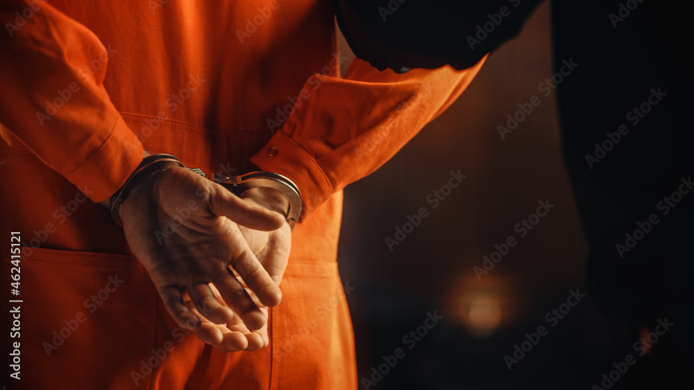 Cinematic Close Up Footage of a Handcuffed Convict at a Law and Justice Court Trial. Handcuffs on Accused Criminal in Orange Jail Jumpsuit. Law Offender Sentenced to Serve Jail Time. - obrazy, fototapety, plakaty 