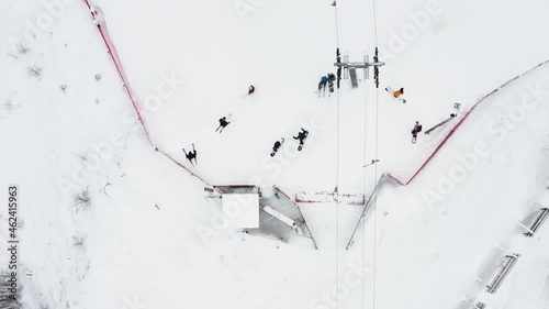 Close up top view from drone on cable way in ski resort. Ski lift elevator transporting skiers and snowboarders on snowy winter slope at mountain resort