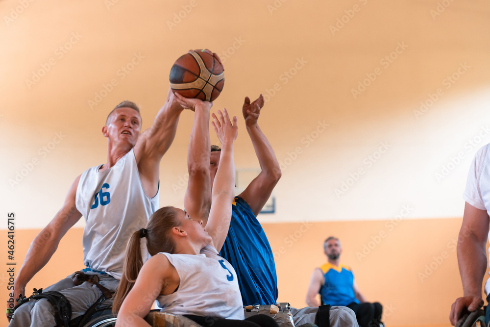 Fototapeta premium Disabled War veterans mixed race and age basketball teams in wheelchairs playing a training match in a sports gym hall. Handicapped people rehabilitation and inclusion concept